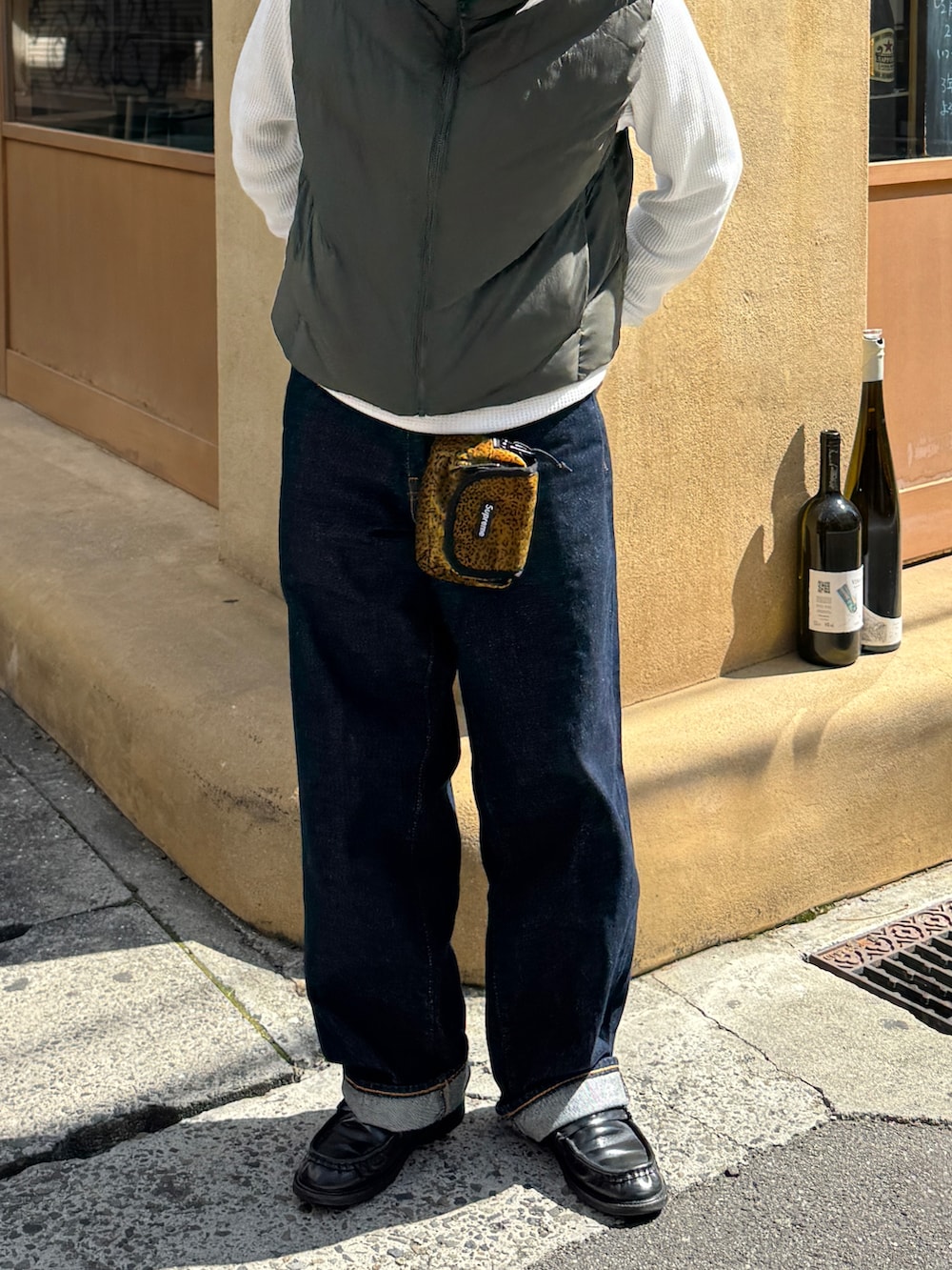 ブルー系のデニムパンツ、グリーン系のダウンベスト、ブラック系のローファーを着用したレディースの春コーディネートの4枚目の写真