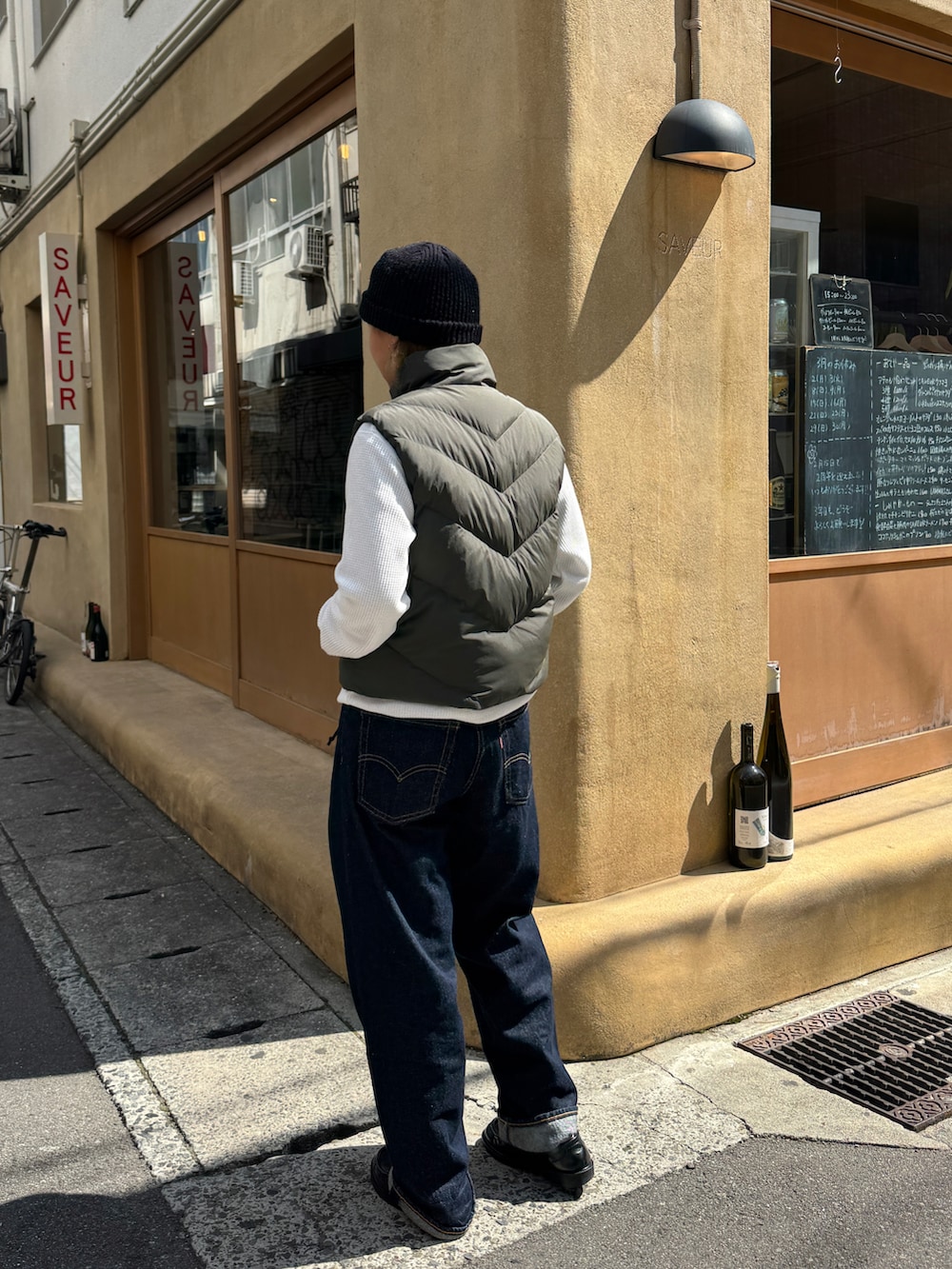 ブルー系のデニムパンツ、グリーン系のダウンベスト、ブラック系のローファーを着用したレディースの春コーディネートの3枚目の写真