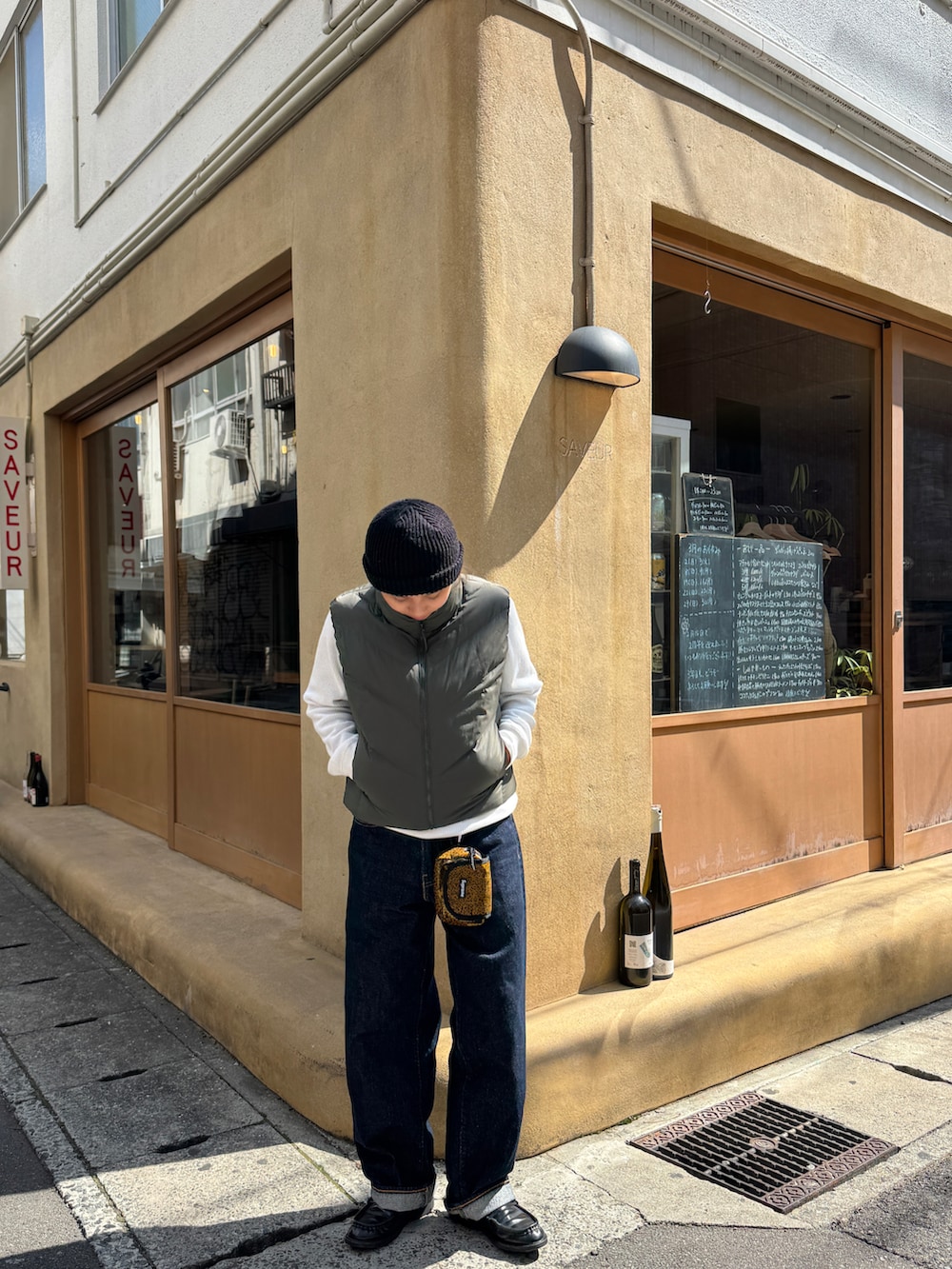 ブルー系のデニムパンツ、グリーン系のダウンベスト、ブラック系のローファーを着用したレディースの春コーディネートの2枚目の写真