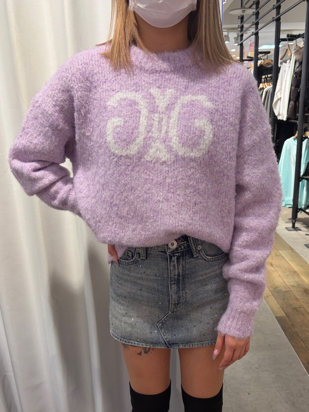 パープル系のニット/セーター、ブルー系のデニムスカート、ブラック系のブーツを着用したレディースの冬コーディネートの4枚目の写真