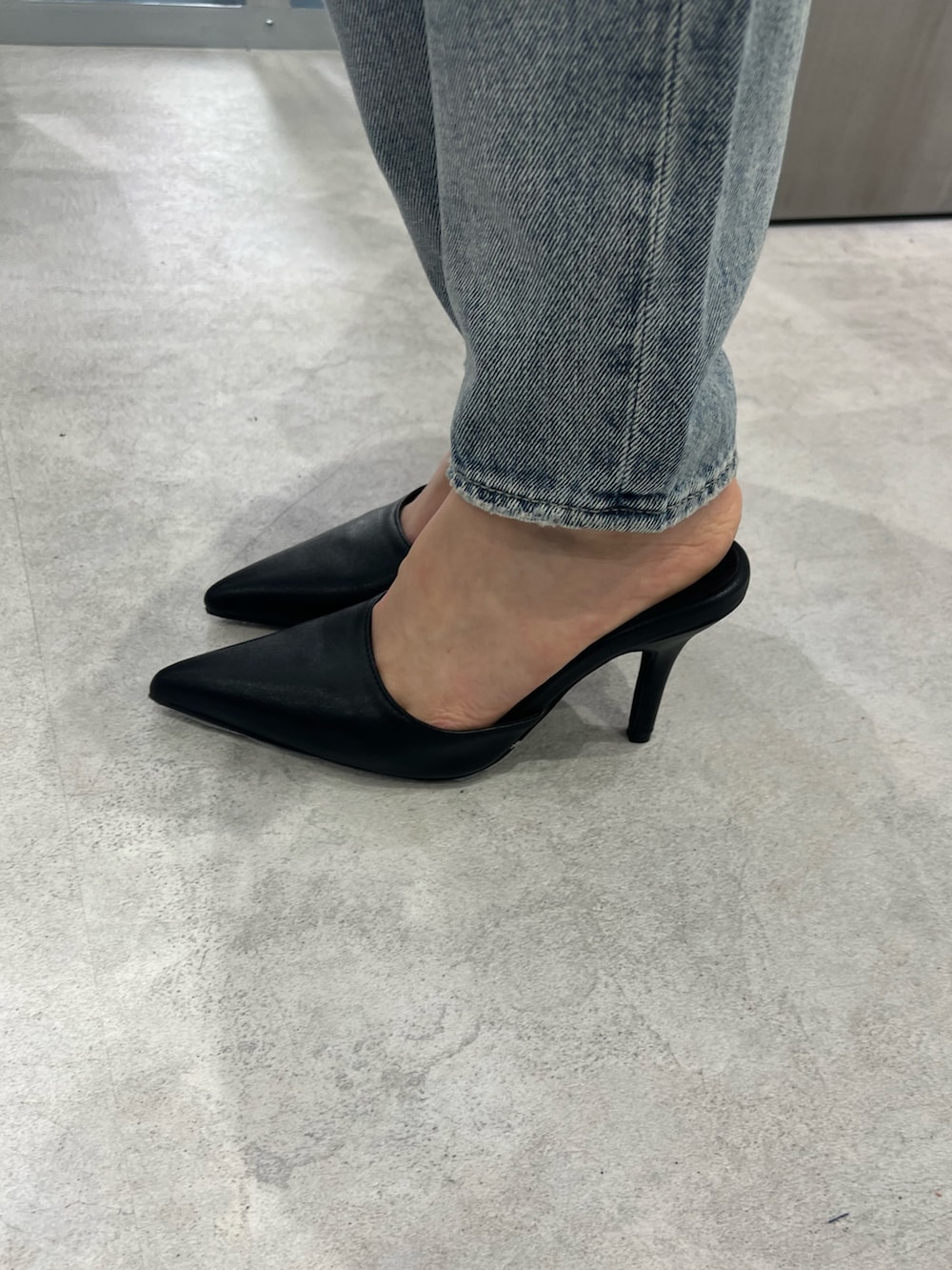ブラック系のニット/セーター、ブルー系のデニムパンツ、ブラック系のパンプスを着用したレディースの春コーディネートの5枚目の写真