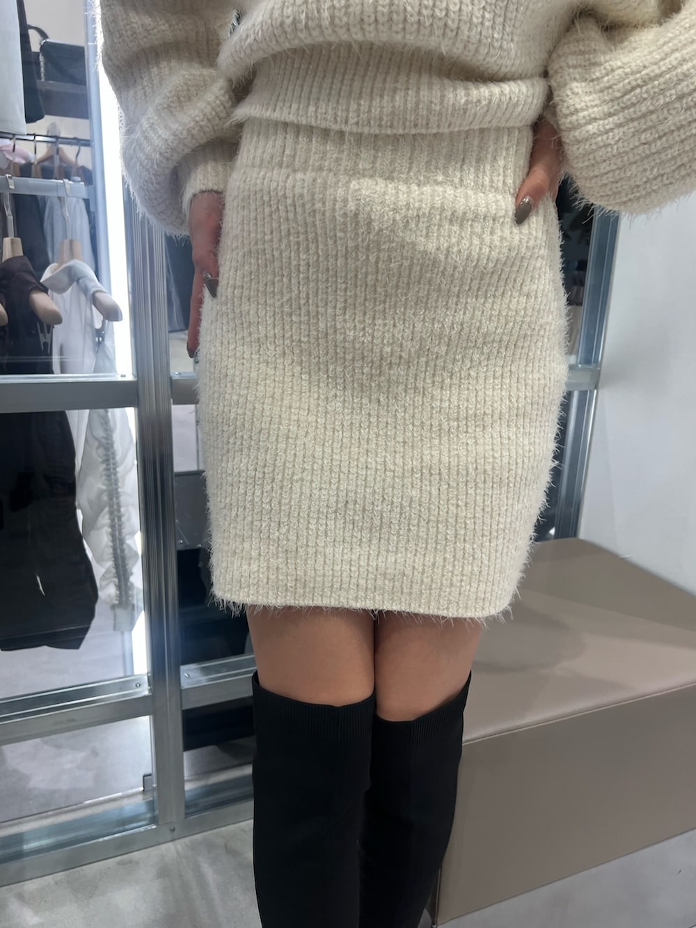 ホワイト系のニット/セーター、ホワイト系のスカート、ブラック系のブーツを着用したレディースの秋コーディネートの4枚目の写真