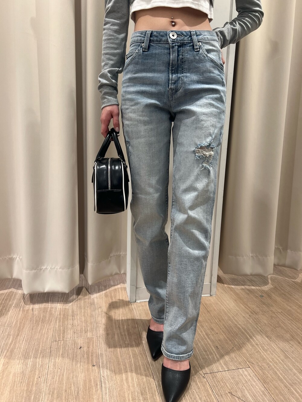 グレー系のTシャツ/カットソー、ブルー系のデニムパンツ、ブラック系のハンドバッグを着用したレディースの冬コーディネートの5枚目の写真