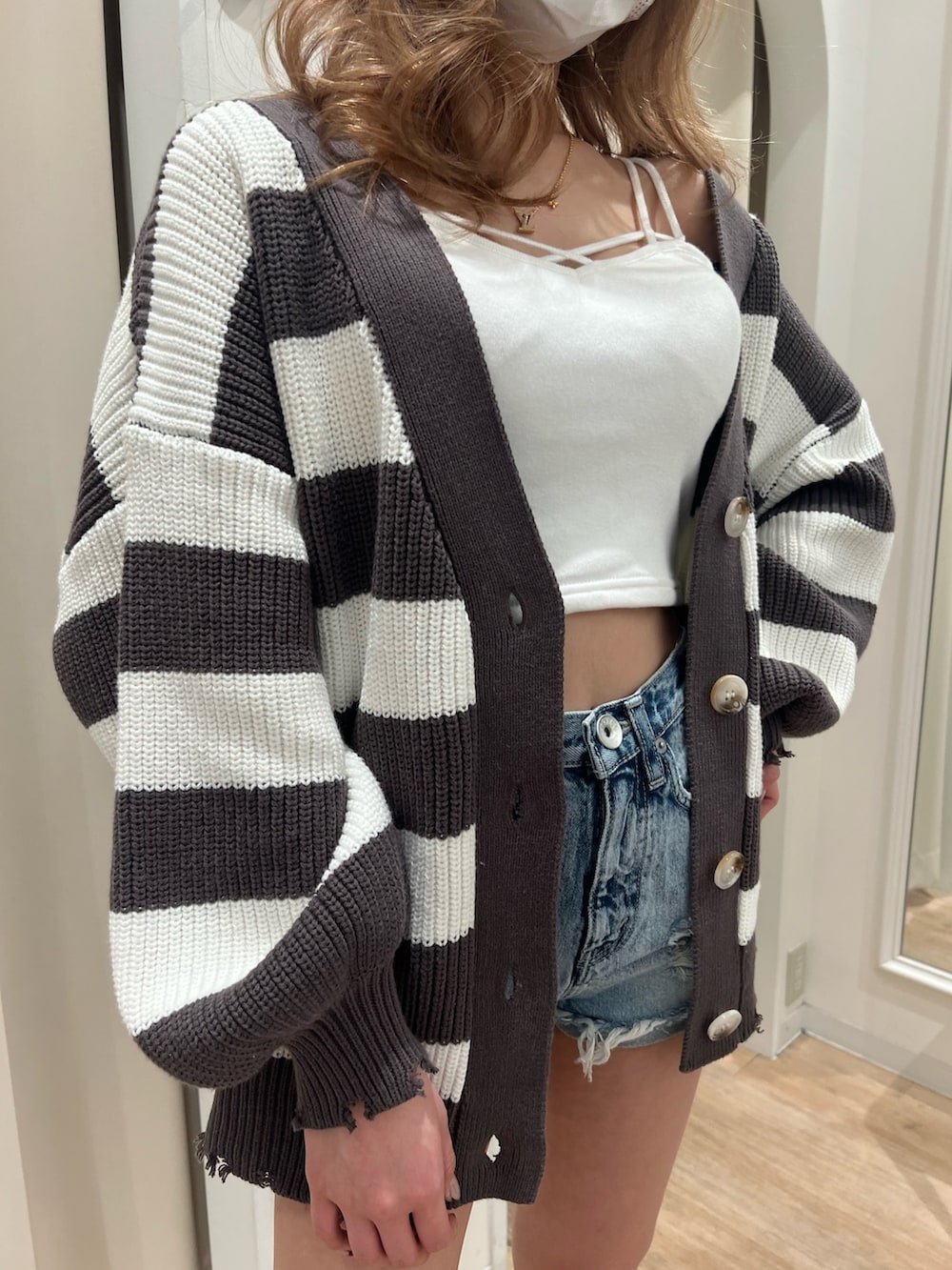 グレー系のカーディガン/ボレロ、ホワイト系のキャミソール、ブルー系のデニムパンツを着用したレディースの春コーディネートの2枚目の写真