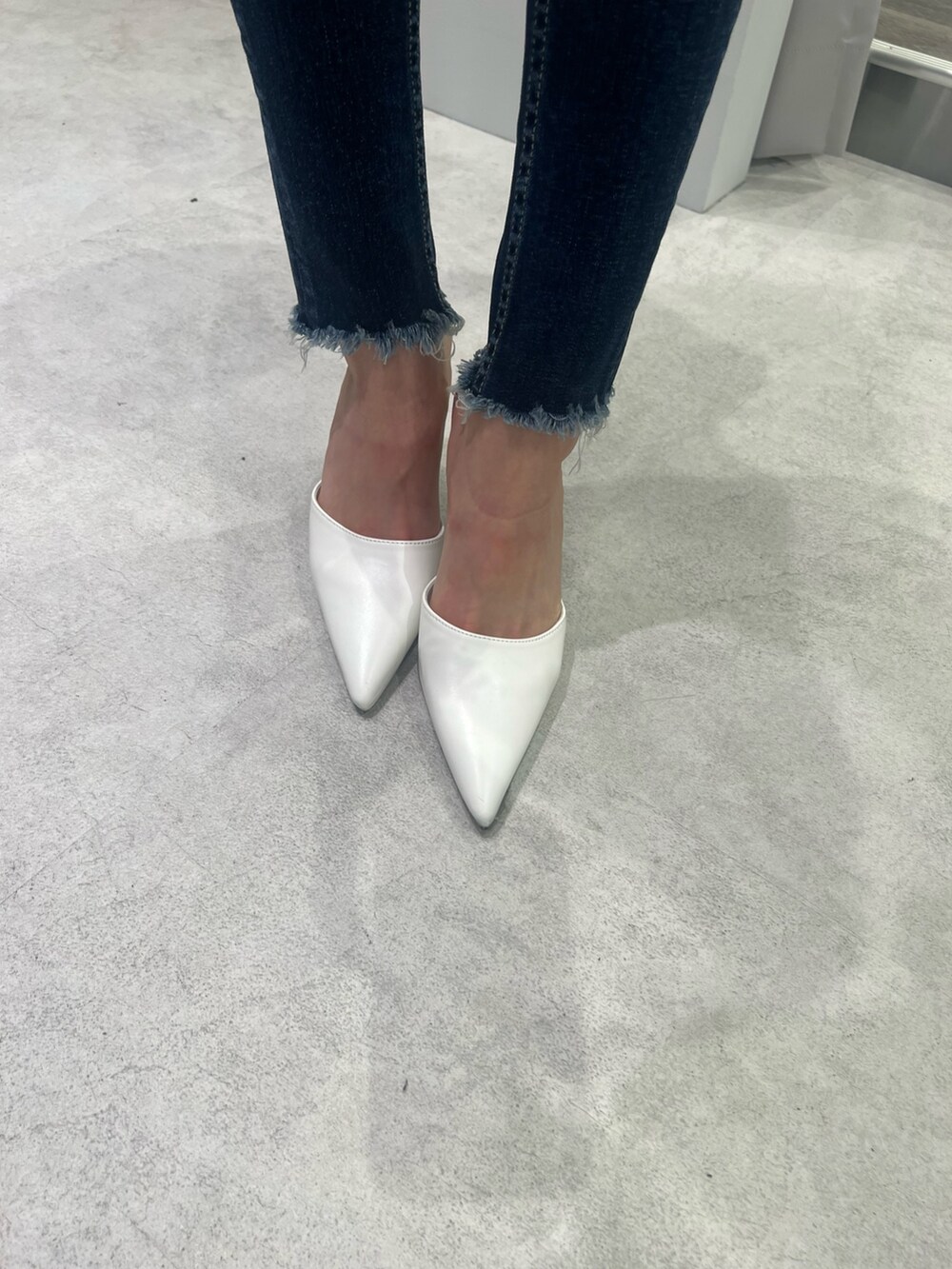 グレー系のニット/セーター、ブルー系のデニムパンツ、ホワイト系のパンプスを着用したレディースの夏コーディネートの5枚目の写真