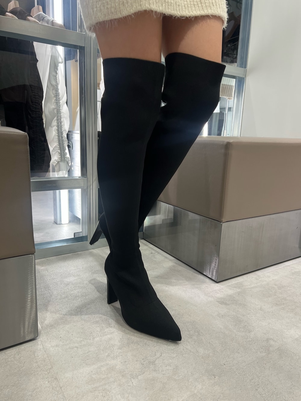 ホワイト系のニット/セーター、ホワイト系のスカート、ブラック系のブーツを着用したレディースの秋コーディネートの5枚目の写真