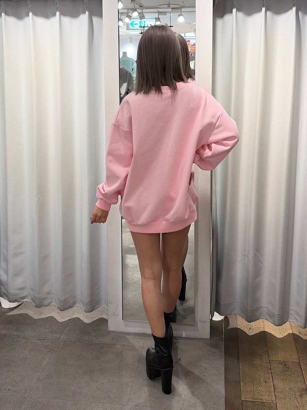 ピンク系のスウェット、ブラック系のブーツを着用したレディースの冬コーディネートの2枚目の写真