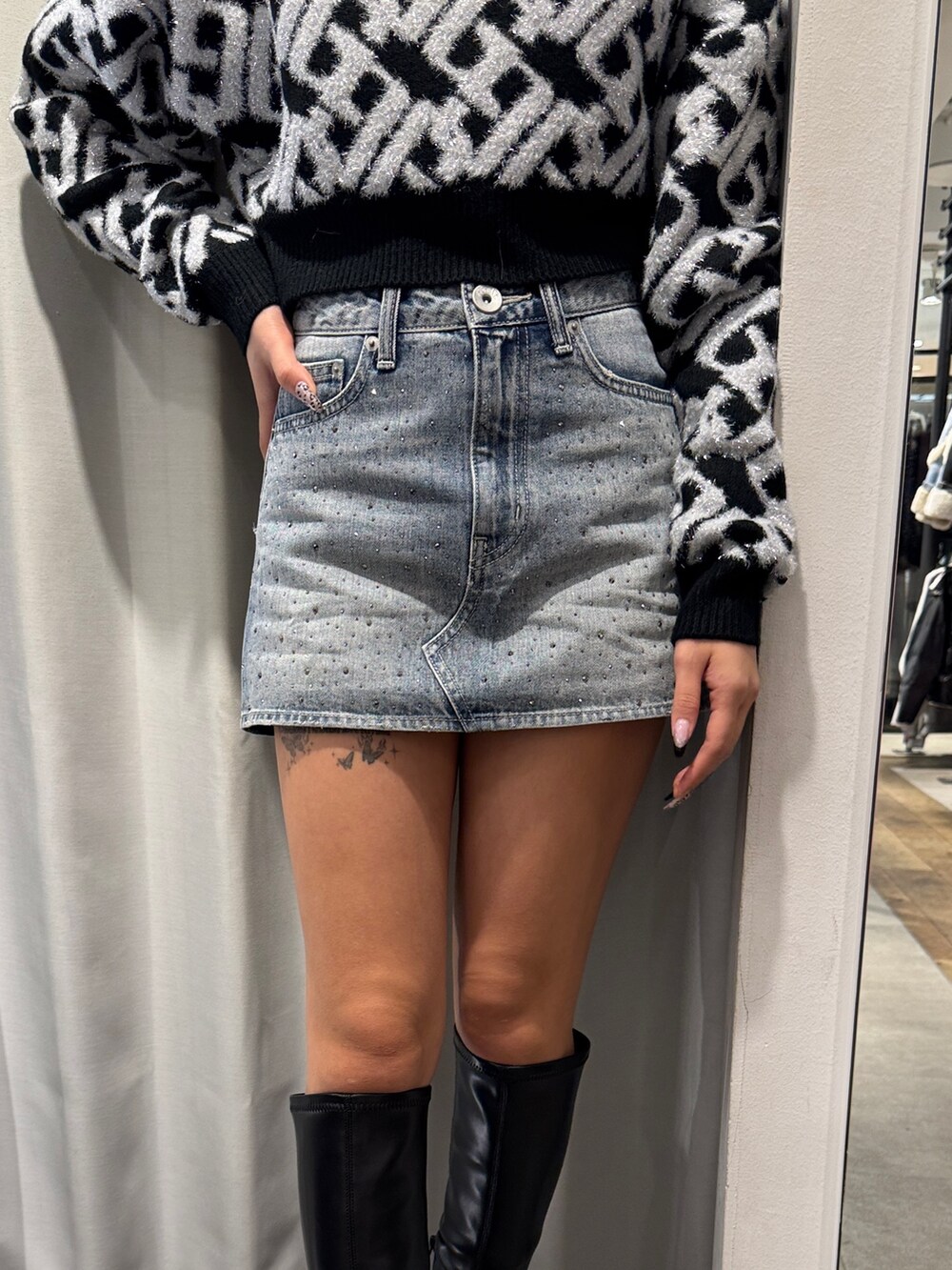 ブラック系のニット/セーター、ブルー系のデニムスカート、ブラック系のブーツを着用したレディースの冬コーディネートの5枚目の写真