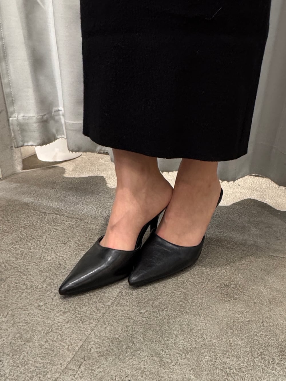 ブラック系のワンピース、ホワイト系のショルダーバッグ、ブラック系のパンプスを着用したレディースの冬コーディネートの5枚目の写真