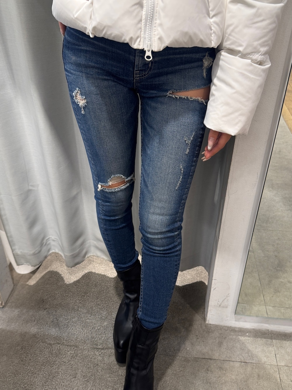 ホワイト系のダウンジャケット/コート、ブルー系のデニムパンツ、ブラック系のブーツを着用したレディースの秋コーディネートの5枚目の写真