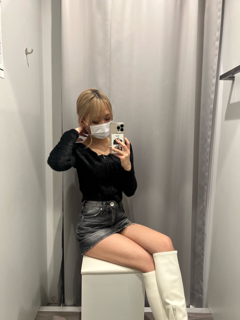 ブラック系のニット/セーター、ブラック系のデニムスカート、ホワイト系のブーツを着用したレディースの秋コーディネートの2枚目の写真