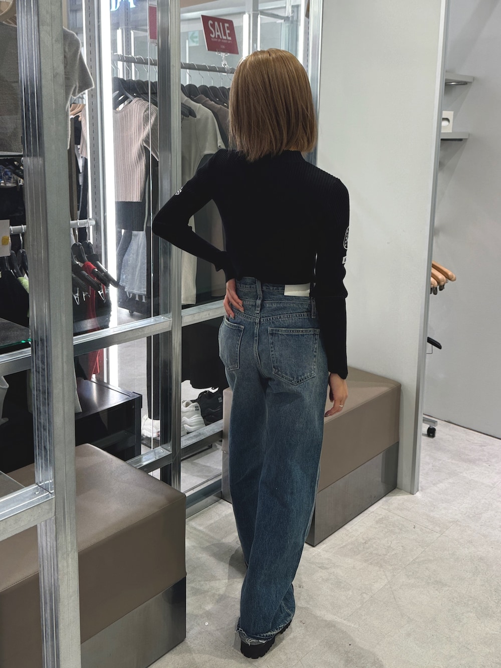 ブラック系のニット/セーター、ブルー系のデニムパンツ、ブラック系のブーツを着用したレディースの秋コーディネートの3枚目の写真