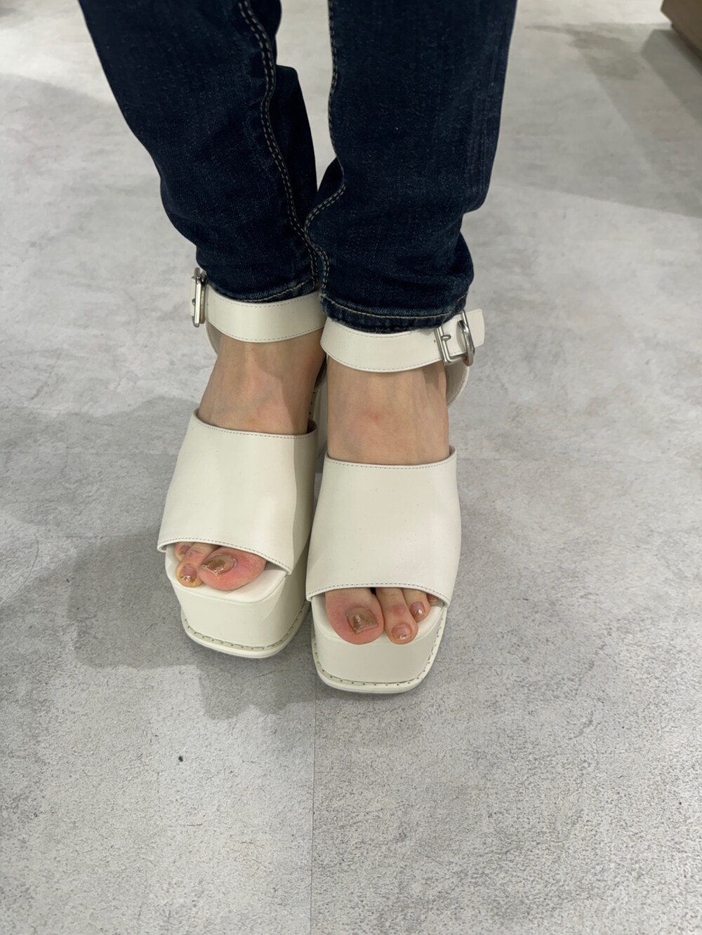 ブラック系のTシャツ/カットソー、ブルー系のデニムパンツ、ホワイト系のサンダルを着用したレディースの夏コーディネートの6枚目の写真