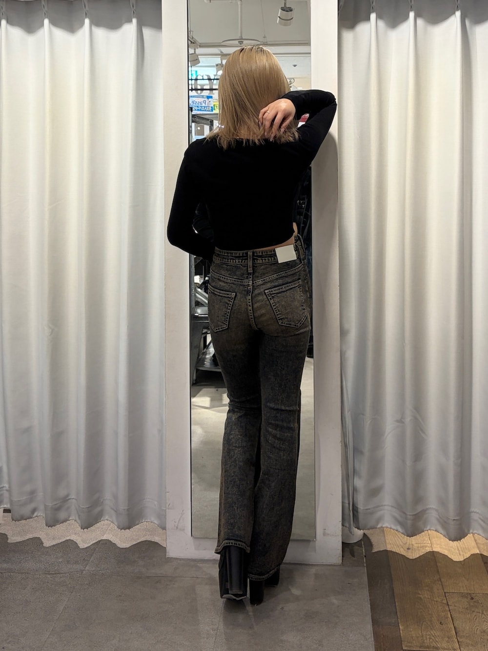 ブラック系のニット/セーター、ブルー系のデニムパンツ、ブラック系のブーツを着用したレディースの冬コーディネートの2枚目の写真