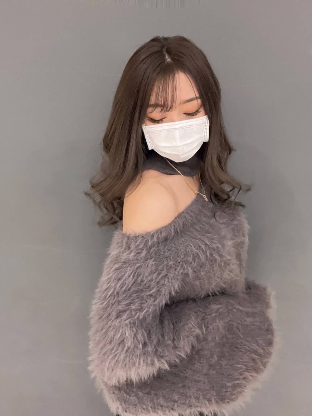 グレー系のニット/セーター、ブラック系のデニムパンツ、ホワイト系のパンプスを着用したレディースの冬コーディネートの2枚目の写真