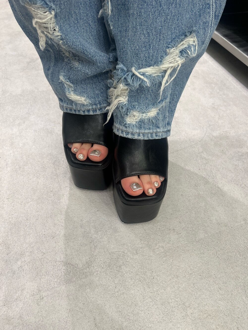 グレー系のパーカー、ブルー系のデニムパンツ、ブラック系のサンダルを着用したレディースの夏コーディネートの5枚目の写真