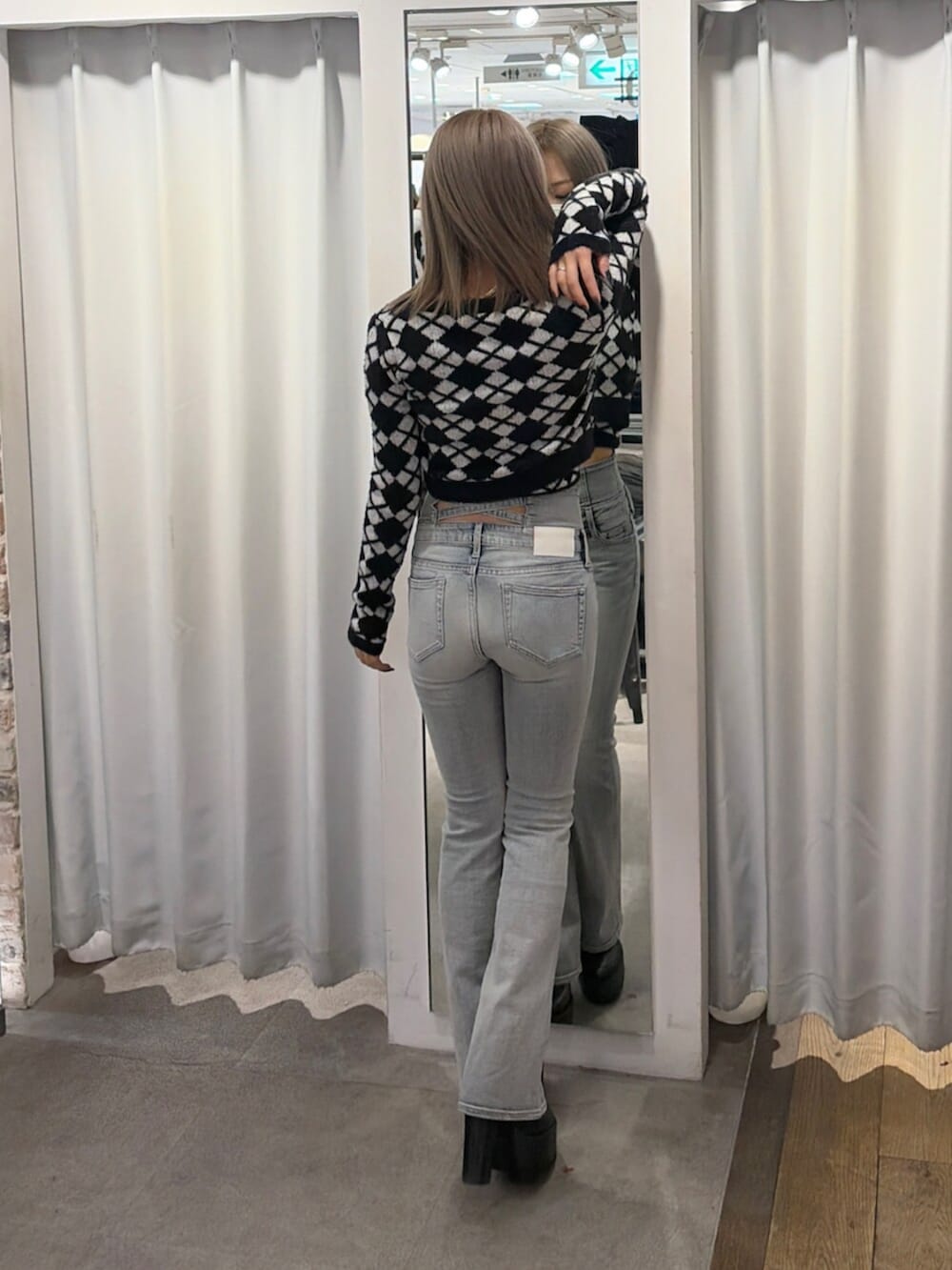 ブラック系のブーツ、ブルー系のデニムパンツ、ブラック系のキャミソールを着用したレディースの冬コーディネートの2枚目の写真