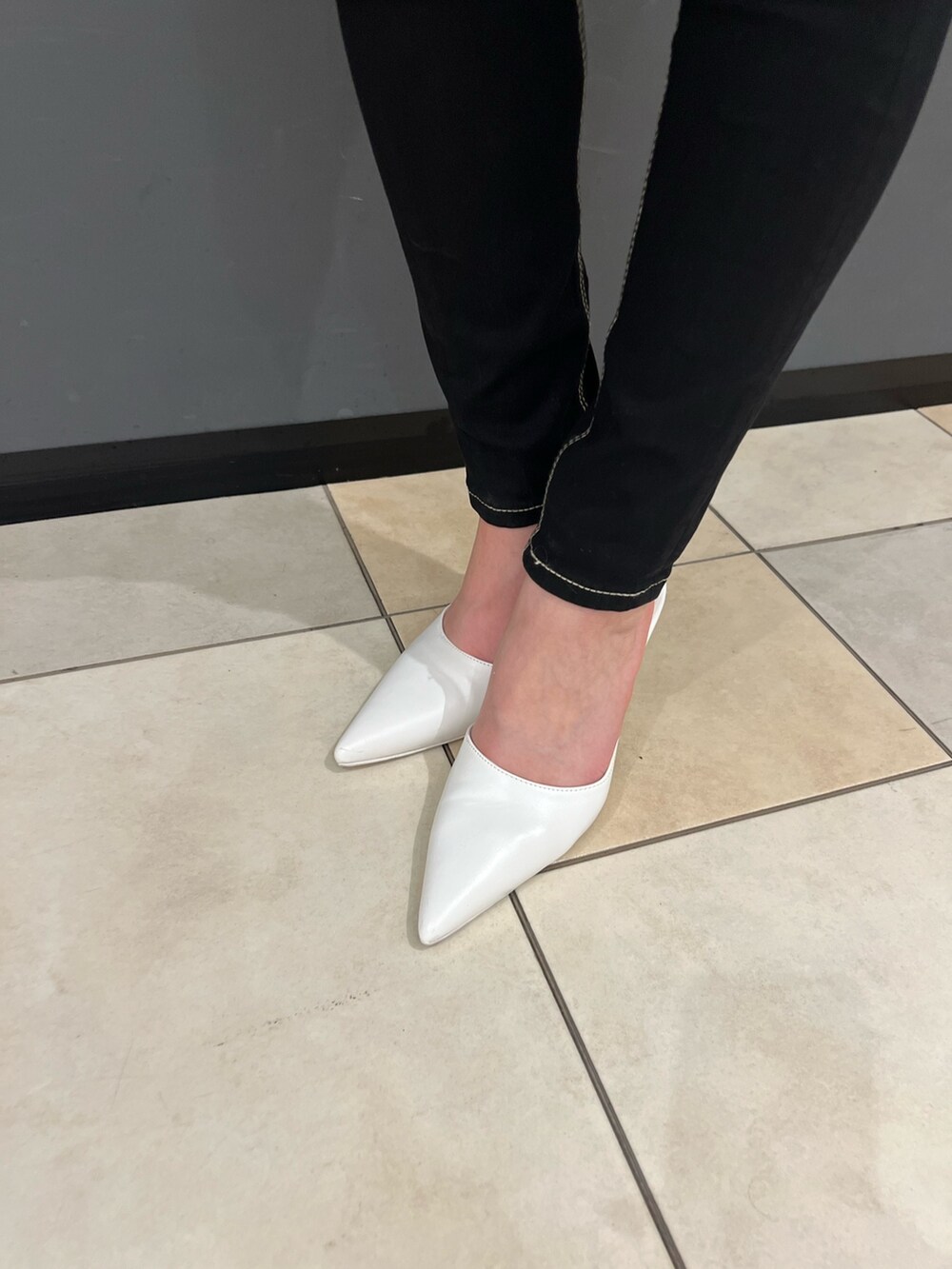 グレー系のニット/セーター、ブラック系のデニムパンツ、ホワイト系のパンプスを着用したレディースの冬コーディネートの5枚目の写真