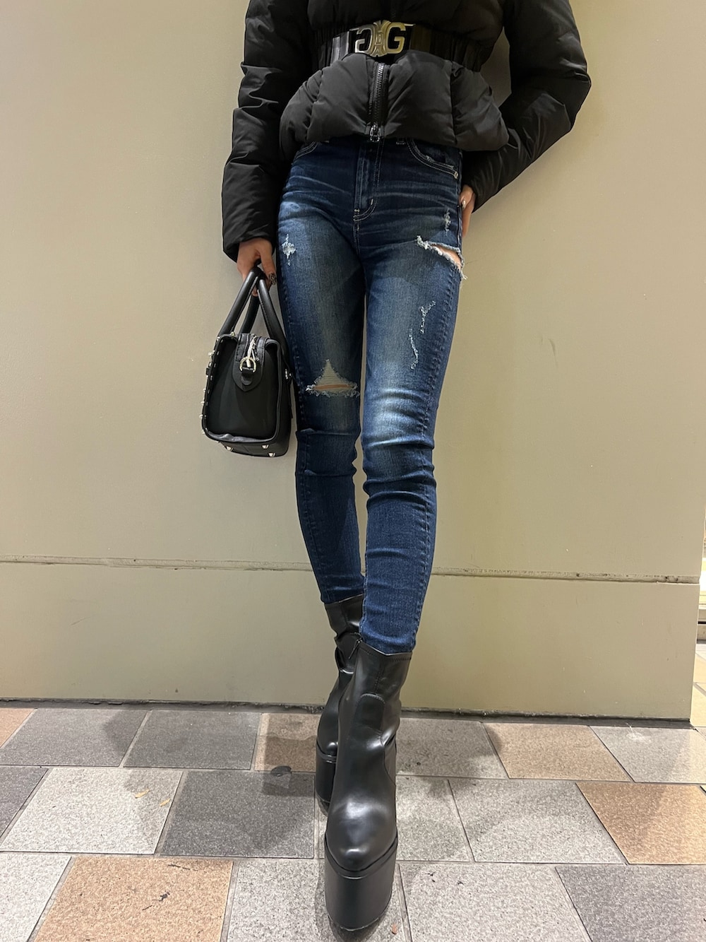 ブラック系のダウンジャケット/コート、ブルー系のデニムパンツ、ブラック系のブーツを着用したレディースの秋コーディネートの3枚目の写真