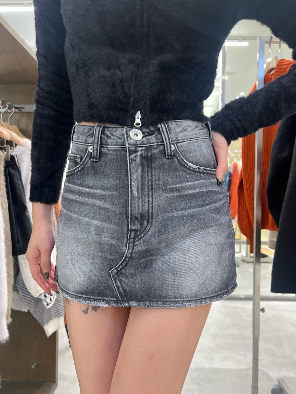 ブラック系のニット/セーター、ブラック系のデニムスカート、ホワイト系のブーツを着用したレディースの秋コーディネートの4枚目の写真