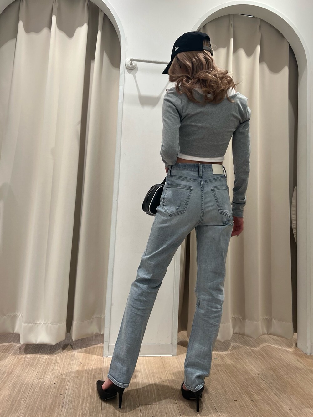 グレー系のTシャツ/カットソー、ブルー系のデニムパンツ、ブラック系のハンドバッグを着用したレディースの冬コーディネートの3枚目の写真