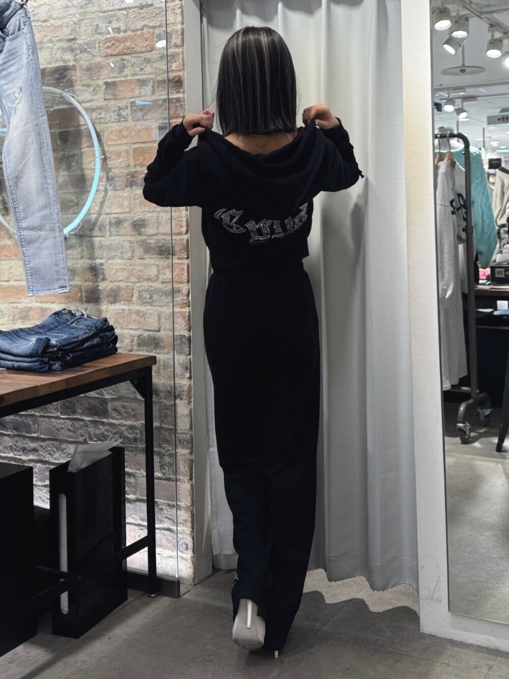 ホワイト系のパンプス、ブラック系のパーカー、ブラック系のスウェットパンツを着用したレディースの冬コーディネートの3枚目の写真