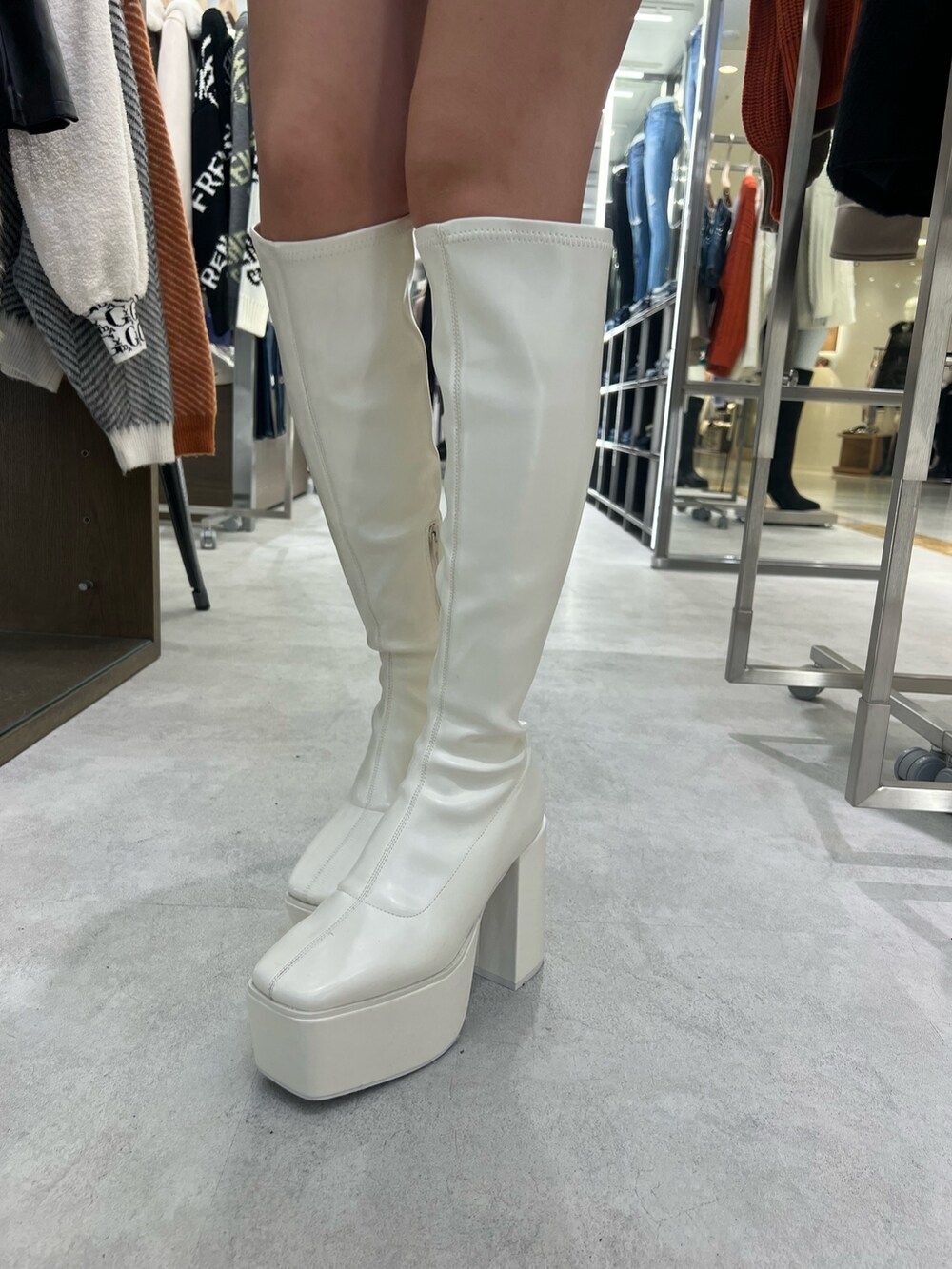 ブラック系のニット/セーター、ブラック系のデニムスカート、ホワイト系のブーツを着用したレディースの秋コーディネートの5枚目の写真