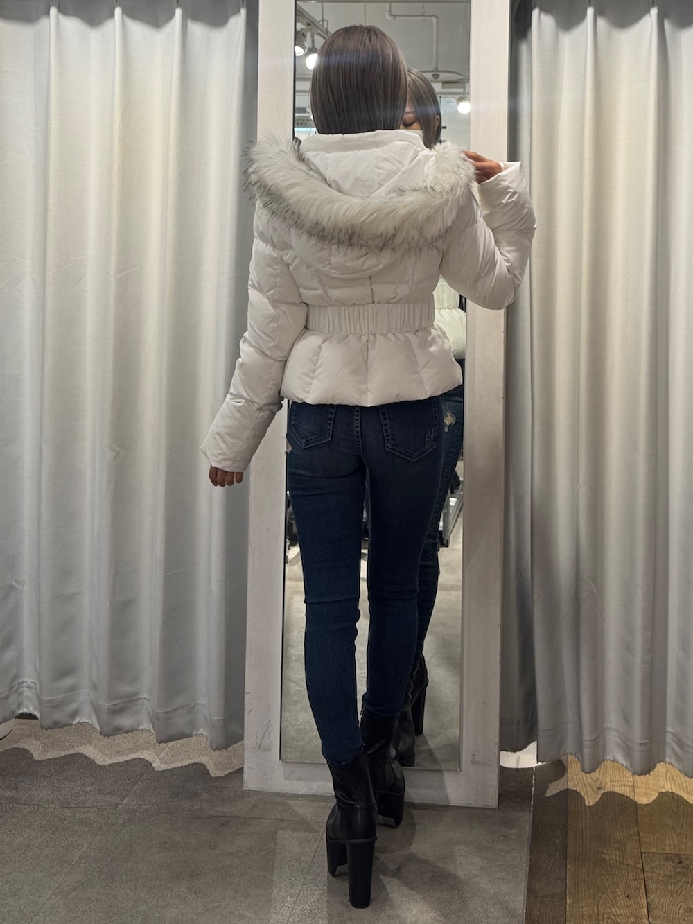 ホワイト系のダウンジャケット/コート、ブルー系のデニムパンツ、ブラック系のブーツを着用したレディースの秋コーディネートの2枚目の写真