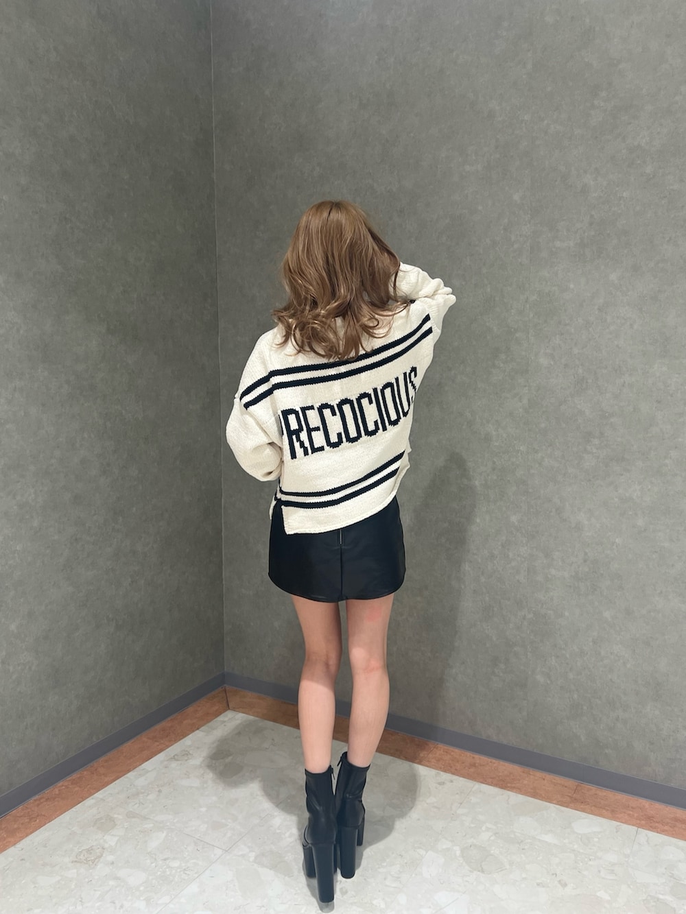 ホワイト系のニット/セーター、ブラック系のスカート、ブラック系のブーツを着用したレディースの冬コーディネートの2枚目の写真