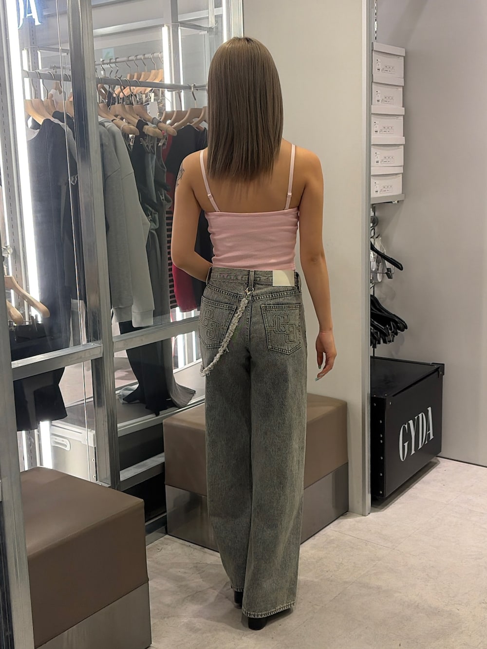 ピンク系のキャミソール、ブルー系のデニムパンツ、ブラック系のサンダルを着用したレディースの春コーディネートの2枚目の写真