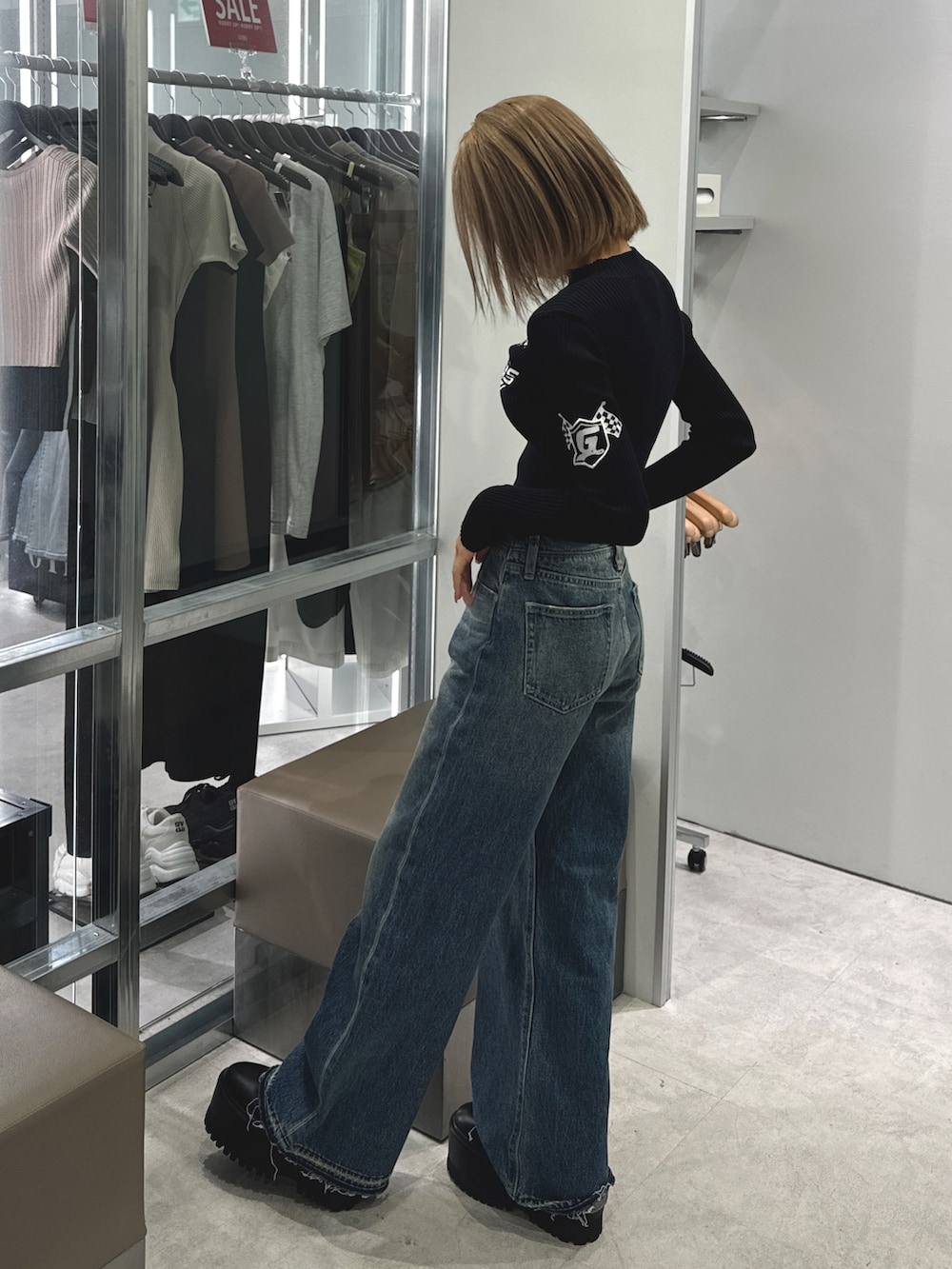 ブラック系のニット/セーター、ブルー系のデニムパンツ、ブラック系のブーツを着用したレディースの秋コーディネートの2枚目の写真