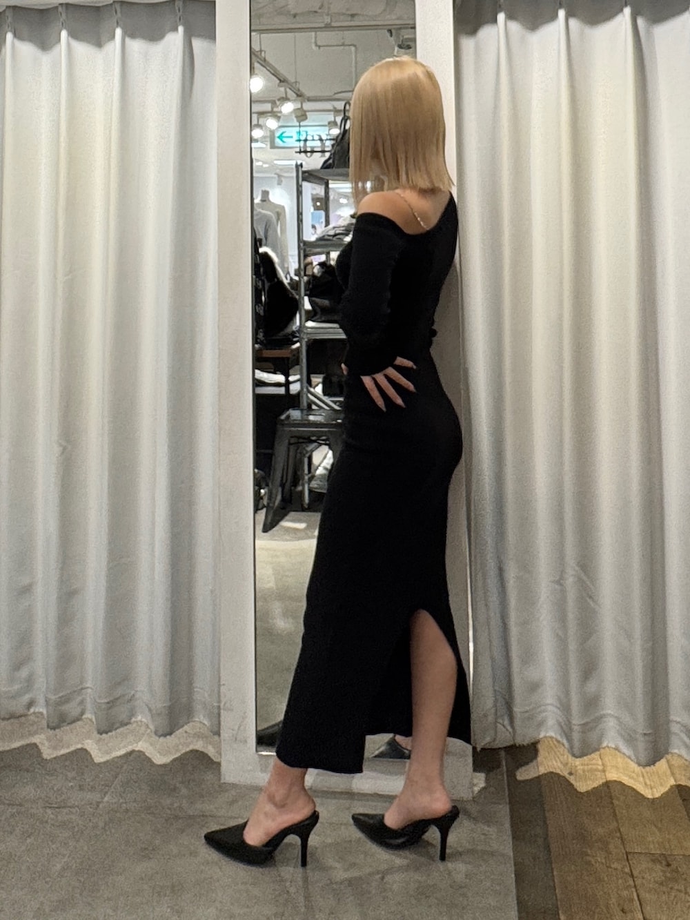 ブラック系のワンピース、ホワイト系のショルダーバッグ、ブラック系のパンプスを着用したレディースの冬コーディネートの3枚目の写真