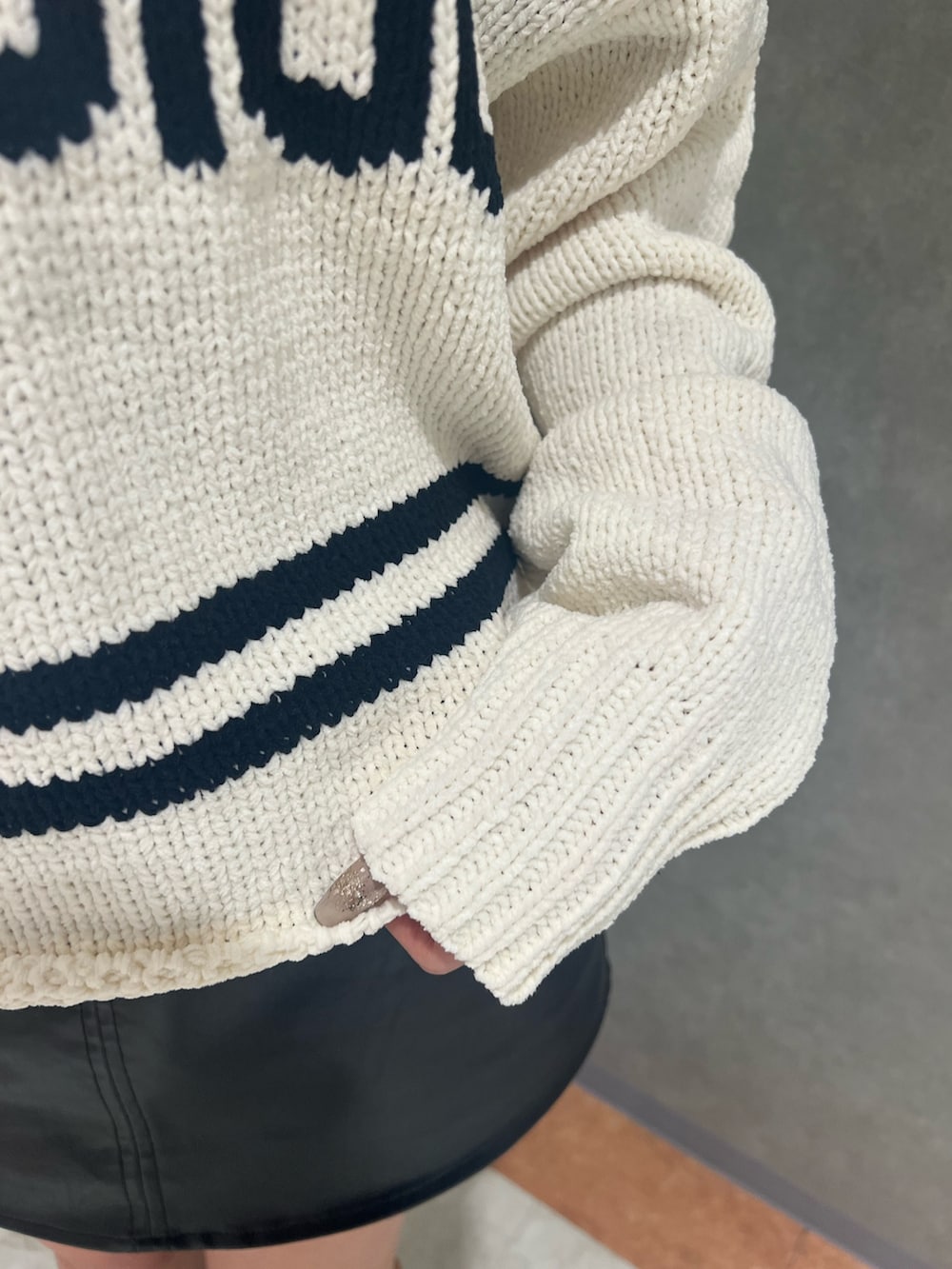 ホワイト系のニット/セーター、ブラック系のスカート、ブラック系のブーツを着用したレディースの冬コーディネートの4枚目の写真