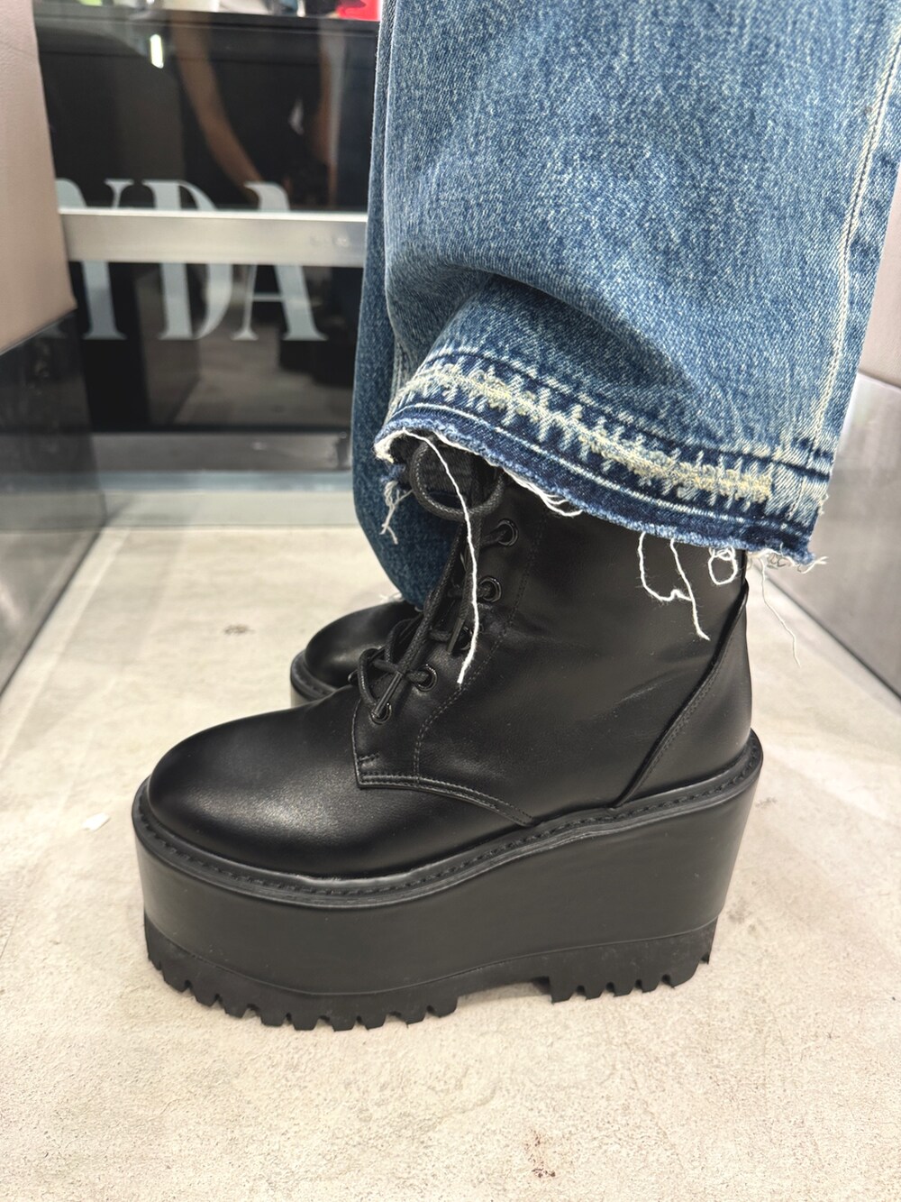ブラック系のニット/セーター、ブルー系のデニムパンツ、ブラック系のブーツを着用したレディースの秋コーディネートの5枚目の写真