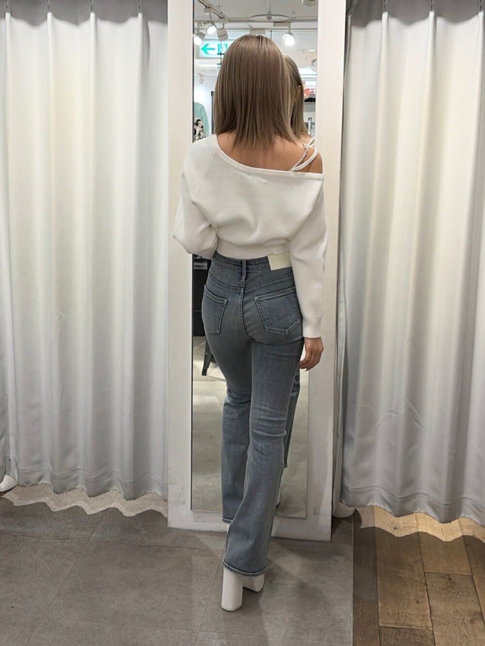 ホワイト系のニット/セーター、ホワイト系のパンプス、ブルー系のデニムパンツを着用したレディースの冬コーディネートの2枚目の写真