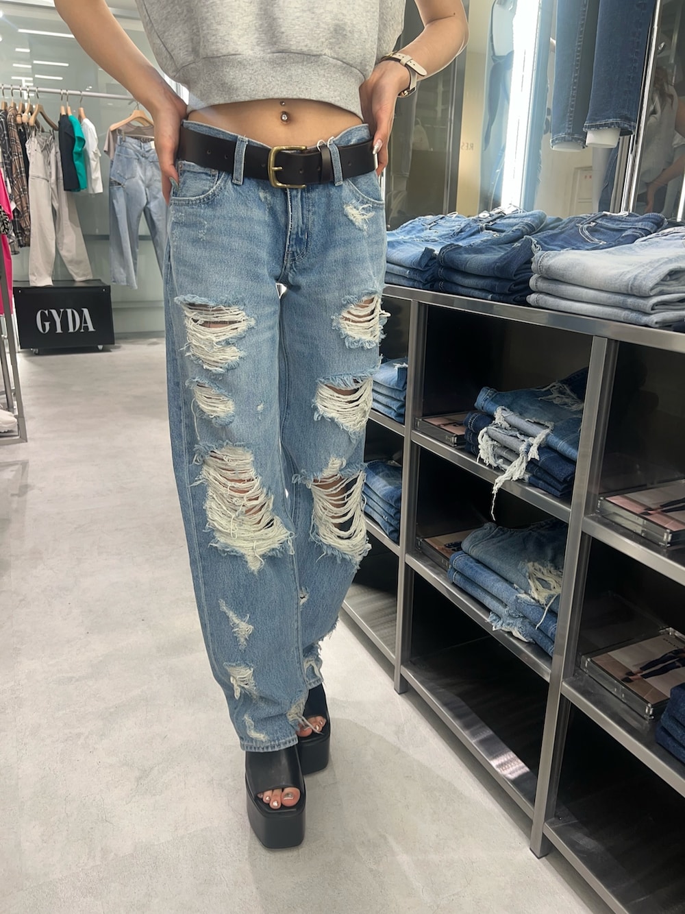 グレー系のパーカー、ブルー系のデニムパンツ、ブラック系のサンダルを着用したレディースの夏コーディネートの4枚目の写真