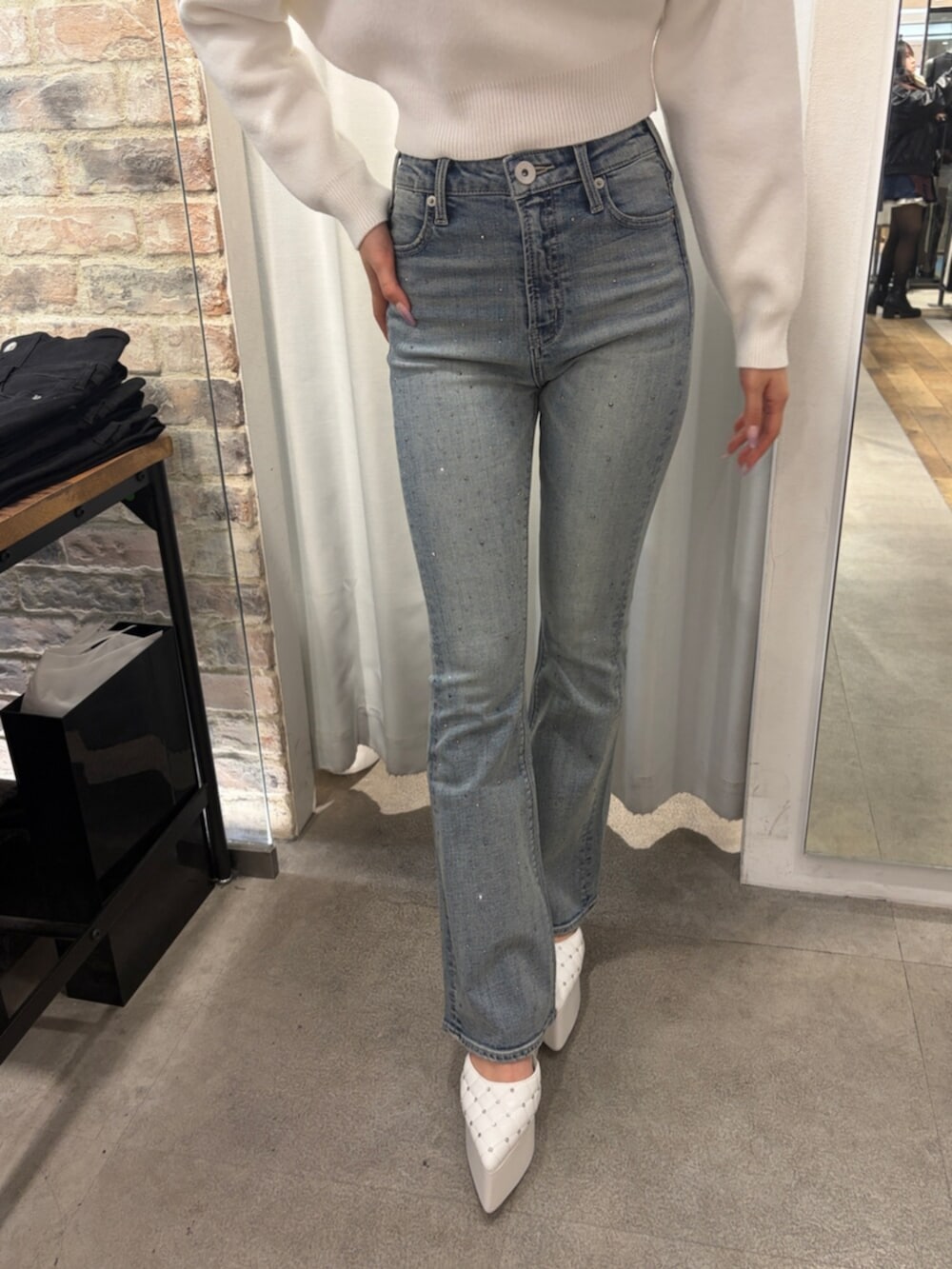 ホワイト系のニット/セーター、ホワイト系のパンプス、ブルー系のデニムパンツを着用したレディースの冬コーディネートの5枚目の写真