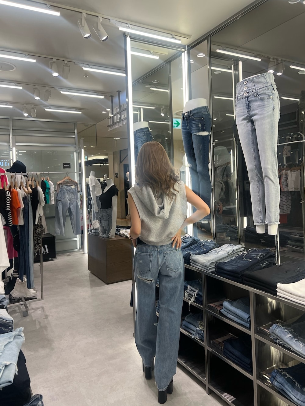 グレー系のパーカー、ブルー系のデニムパンツ、ブラック系のサンダルを着用したレディースの夏コーディネートの2枚目の写真