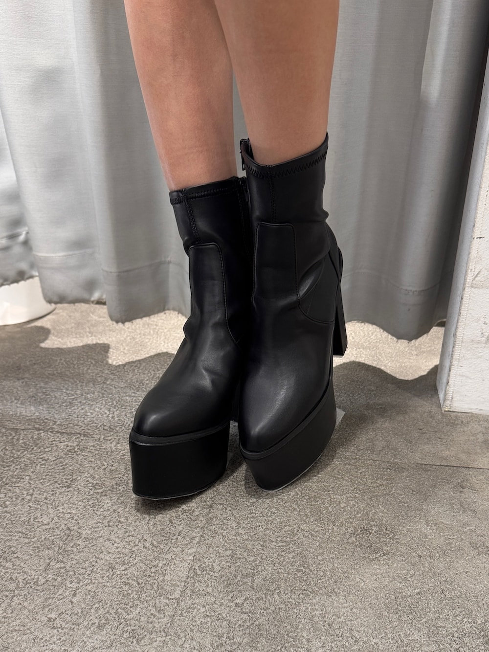 グレー系のパーカー、ブラック系のスカート、ブラック系のブーツを着用したレディースの冬コーディネートの5枚目の写真