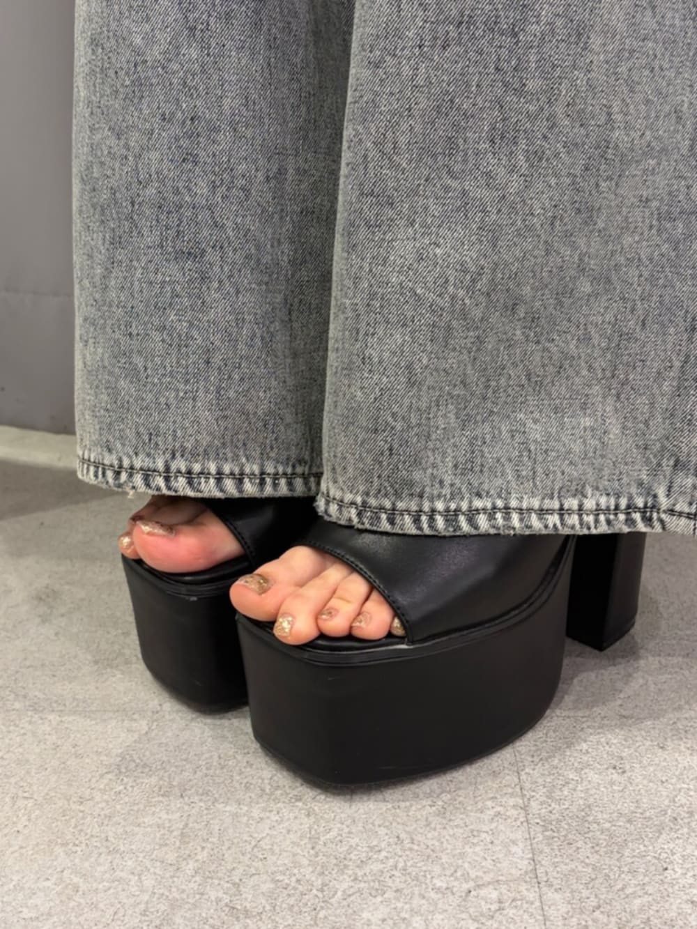 ブラック系のサンダル、ブルー系のデニムパンツ、ホワイト系のタンクトップを着用したレディースの春コーディネートの6枚目の写真