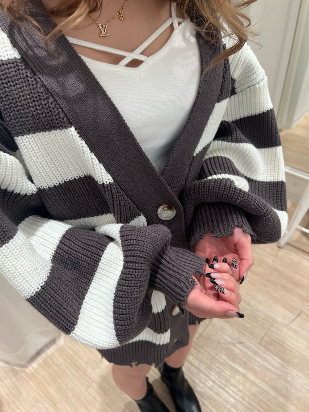 グレー系のカーディガン/ボレロ、ホワイト系のキャミソール、ブルー系のデニムパンツを着用したレディースの春コーディネートの5枚目の写真