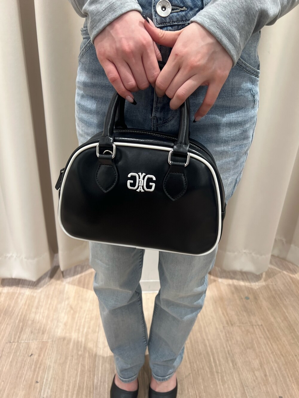 グレー系のTシャツ/カットソー、ブルー系のデニムパンツ、ブラック系のハンドバッグを着用したレディースの冬コーディネートの6枚目の写真