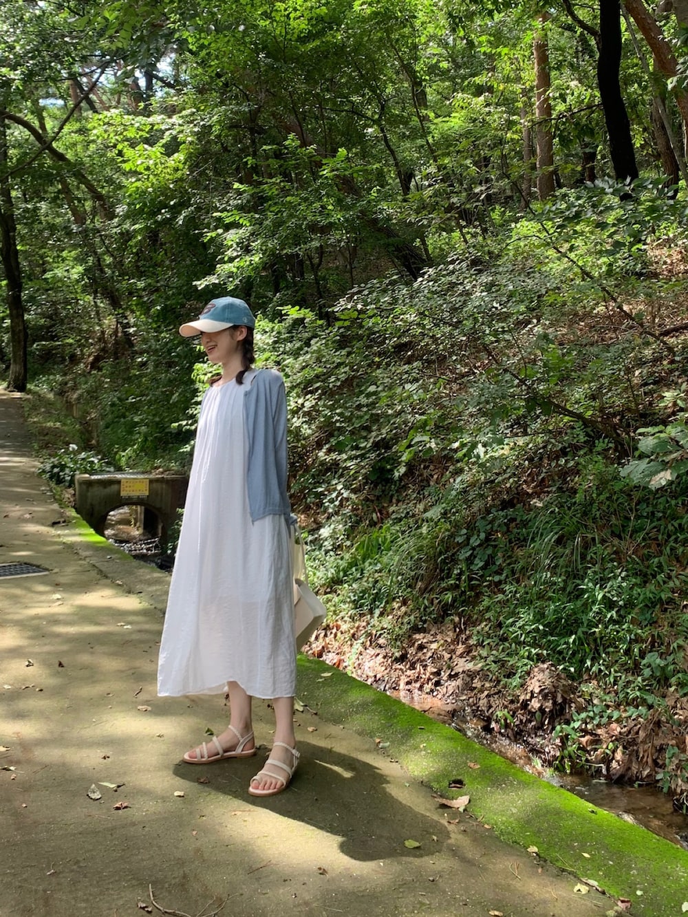 ホワイト系のハンドバッグ、ブルー系のキャップを着用したレディースの秋コーディネートの2枚目の写真