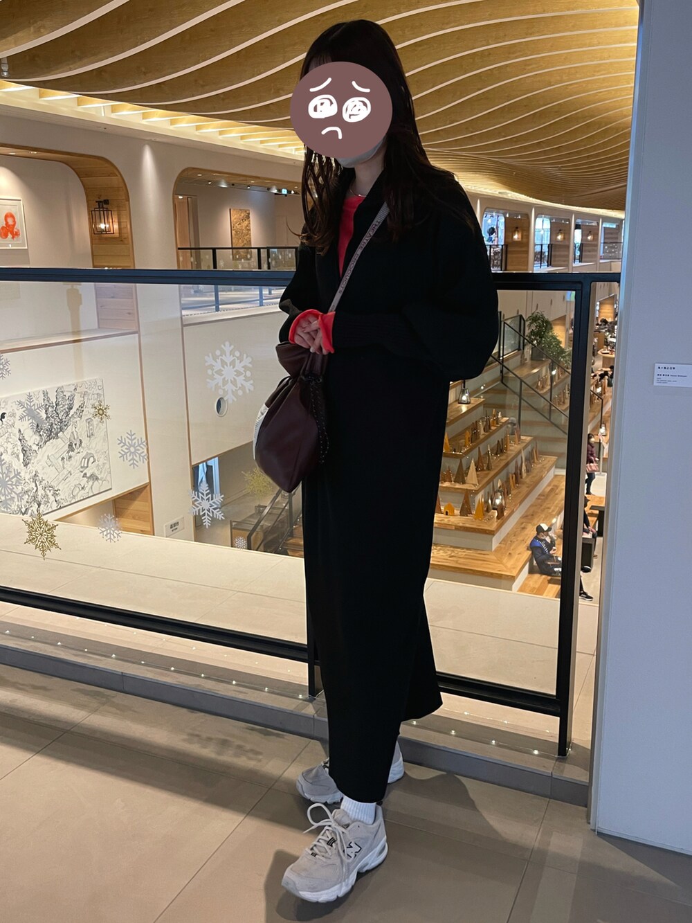 ベージュ系のスニーカー、ブラウン系のショルダーバッグ、ブラック系のワンピースを着用したレディースの冬コーディネートの2枚目の写真