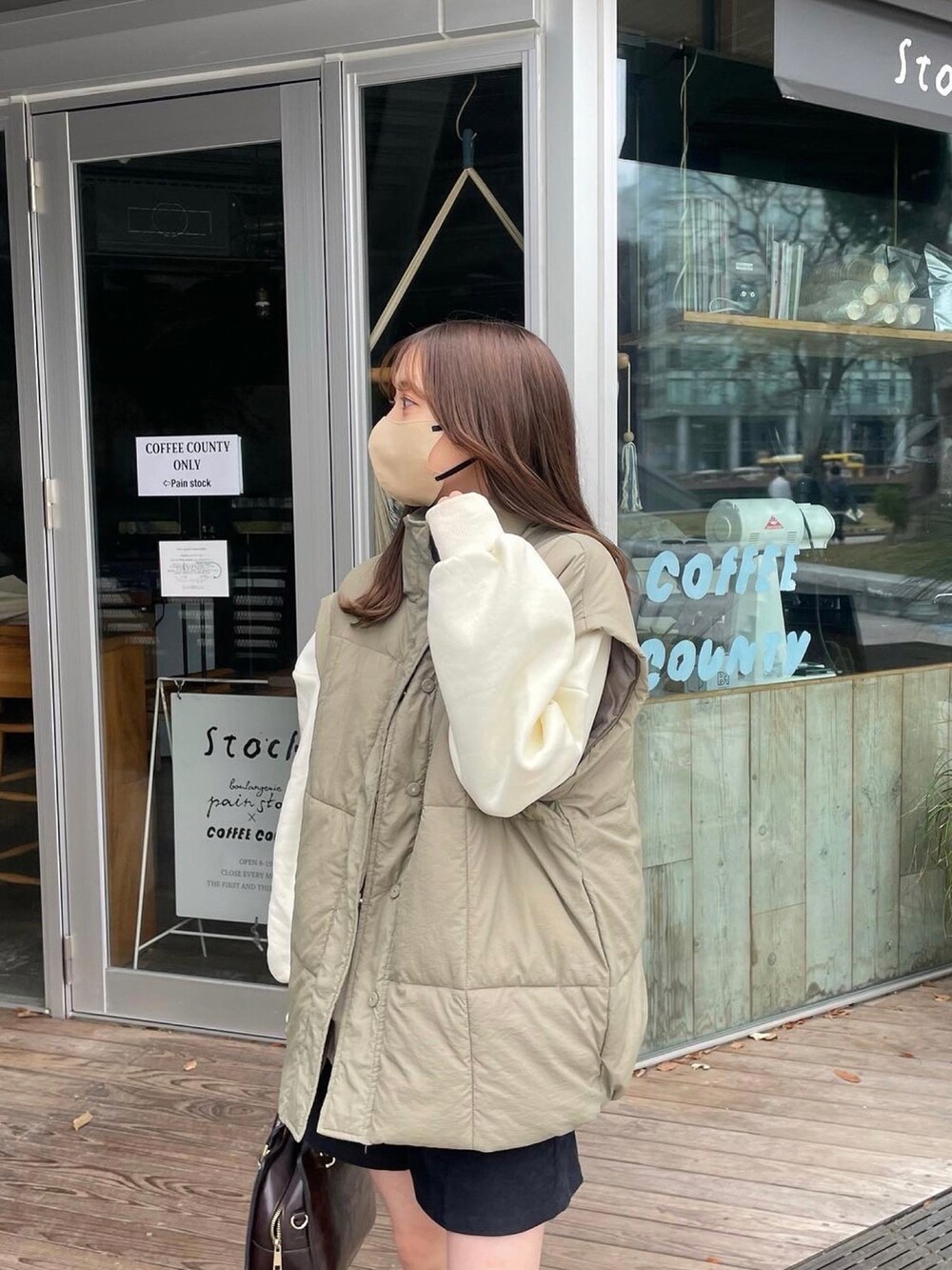 ホワイト系のスウェット、グリーン系のダウンベスト、ブラック系のその他パンツを着用したレディースの冬コーディネートの2枚目の写真