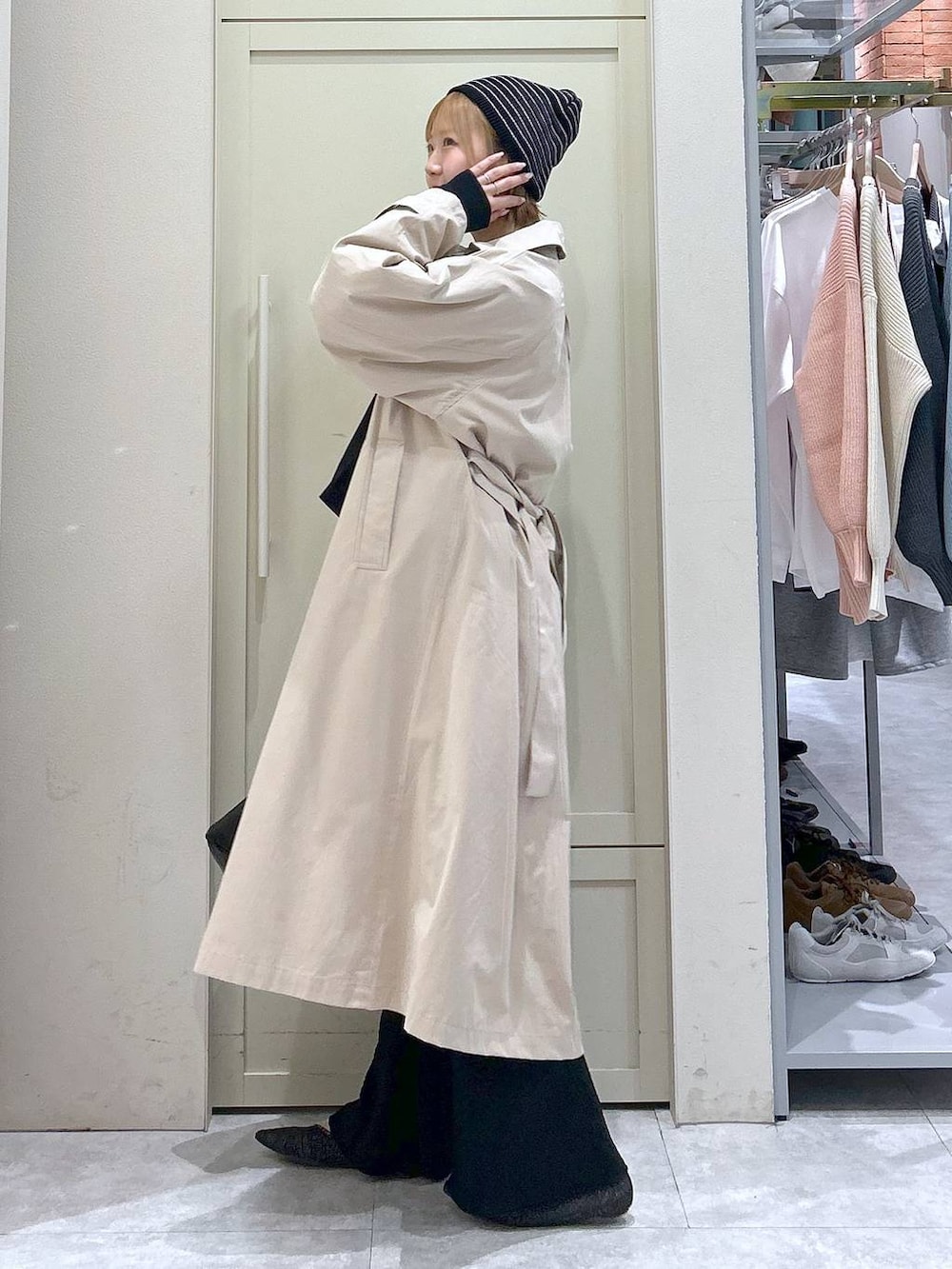 ブラック系のショルダーバッグ、ブラック系のパンプス、ベージュ系のステンカラーコートを着用したレディースの春コーディネートの2枚目の写真