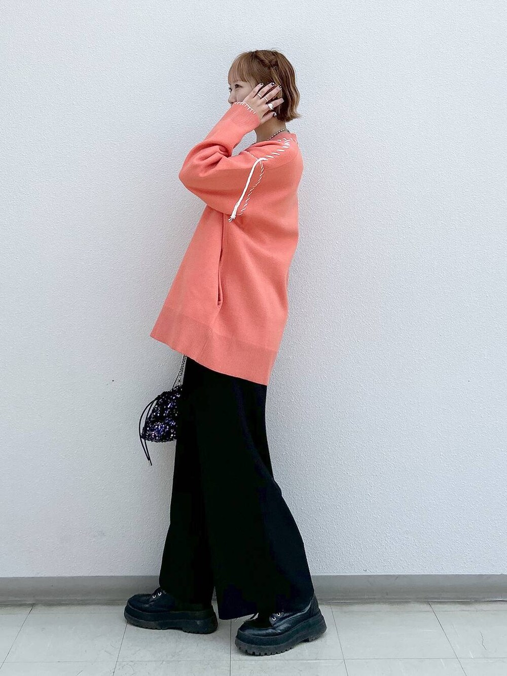 ブラック系のスラックス、ホワイト系のタンクトップ、ブラック系のブーツを着用したレディースの冬コーディネートの2枚目の写真