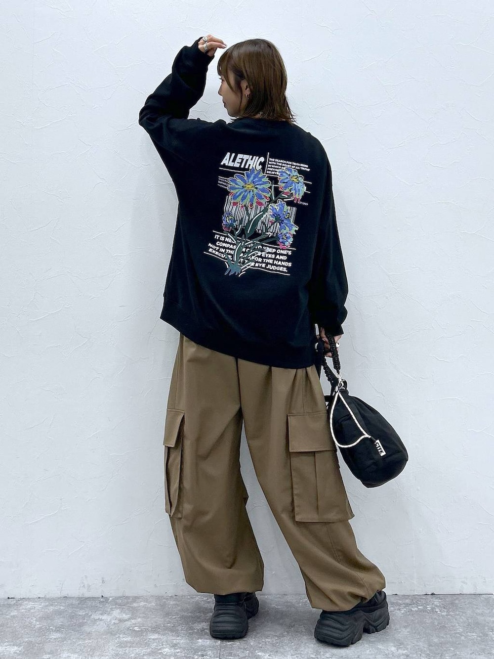 ブラック系のスニーカー、ブラック系のスウェット、ブラック系のショルダーバッグを着用したレディースの秋コーディネートの3枚目の写真