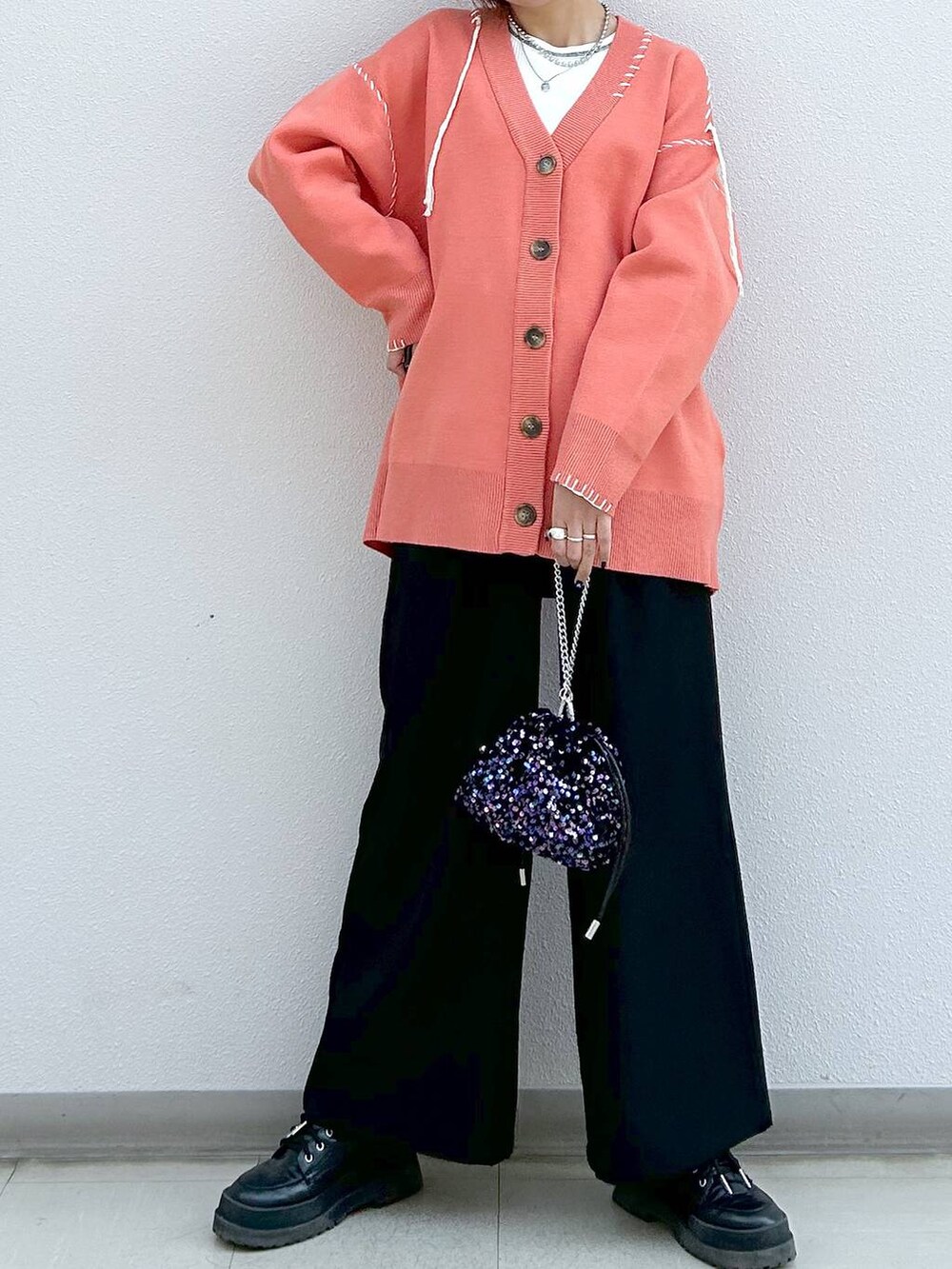 ブラック系のスラックス、ホワイト系のタンクトップ、ブラック系のブーツを着用したレディースの冬コーディネートの4枚目の写真