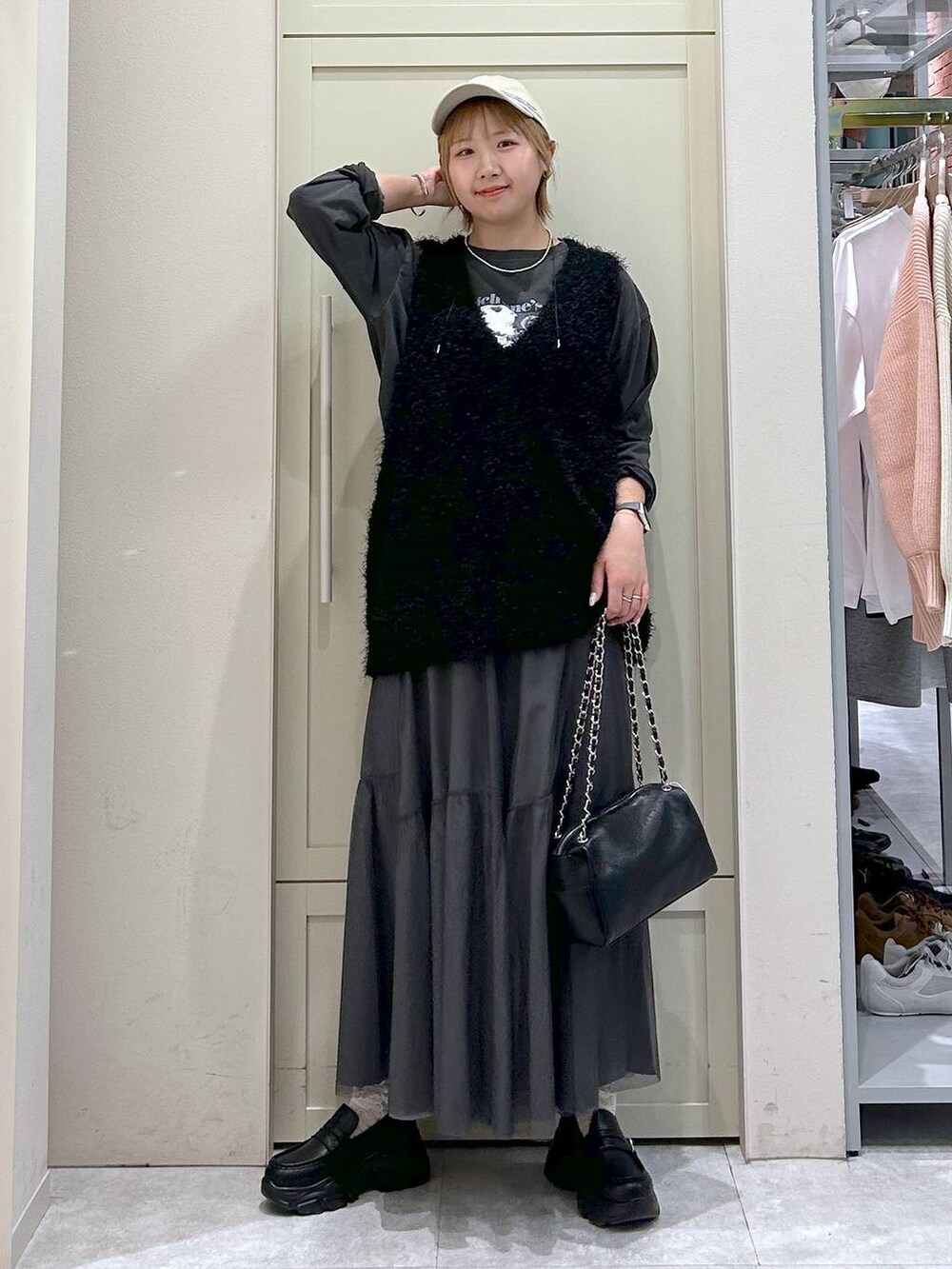 ブラック系のショルダーバッグ、ブラック系のローファー、ブラック系のベストを着用したレディースの春コーディネートの7枚目の写真